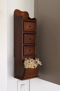 a wooden shelf with drawers and flowers in it