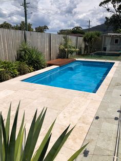 an empty swimming pool in the middle of a backyard with trees and plants around it