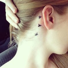a woman with a small black bird tattoo on her left side behind the ear,