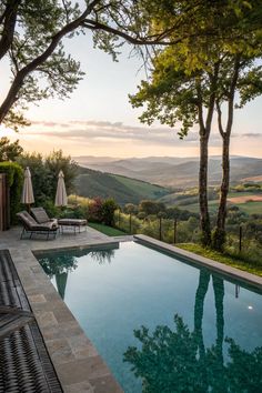 an outdoor swimming pool with lounge chairs and umbrellas overlooking the hills in the distance