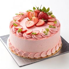 a strawberry cake with pink icing and fresh strawberries on top