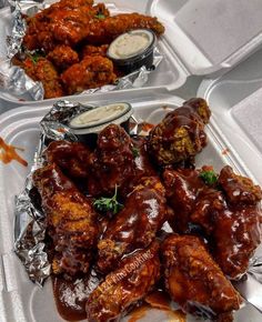 two trays filled with chicken wings covered in sauce