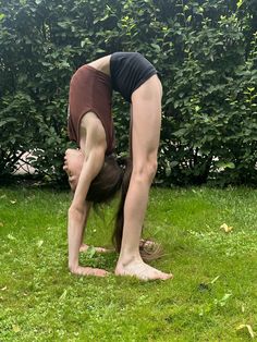 a woman doing a handstand in the grass