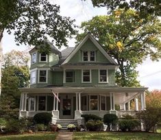 a large green house with white trim and windows