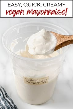 a plastic container filled with yogurt next to a wooden spoon