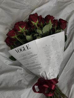 a bouquet of red roses wrapped in paper and tied with a ribbon on a white sheet