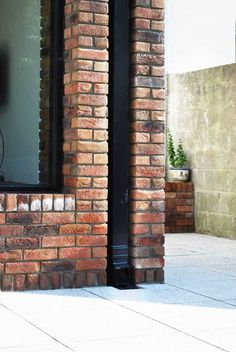 a cat sitting in the window sill of a brick building with a television on it's side