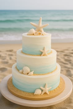 a three tiered wedding cake with starfish and seashells on the beach