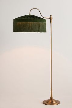 a floor lamp with a green shade on the base and a gold colored metal pole