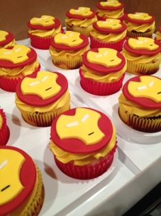 cupcakes with yellow and red frosting are arranged on a white counter top