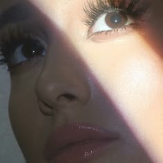 a woman's eyes are shown with long lashes and bright light shining on her face