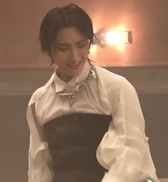 a woman in a white shirt and black dress is holding a cell phone while smiling