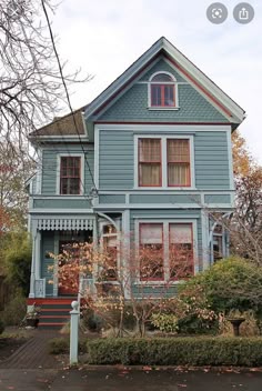 a blue house with red trim on the front and side windows, in autumn time
