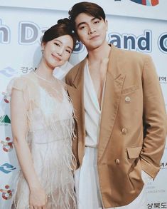 two people standing next to each other on a red carpet