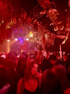 a large group of people standing around in a room with lights on the ceiling and decorations hanging from the ceiling