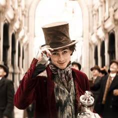 a man wearing a top hat and holding a glass jar in front of his face