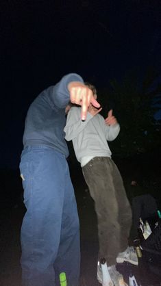 two young men standing next to each other on skateboards in the dark at night