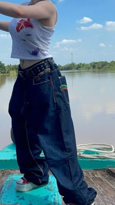a woman standing on the end of a boat in front of a body of water