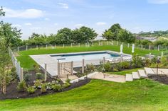 an aerial view of a swimming pool surrounded by trees and grass with stairs leading up to it