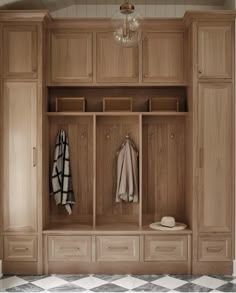 a large wooden closet with two coats hanging on it's doors and some drawers