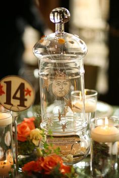 the table is set with candles, flowers and glass jars for numbers to be placed on