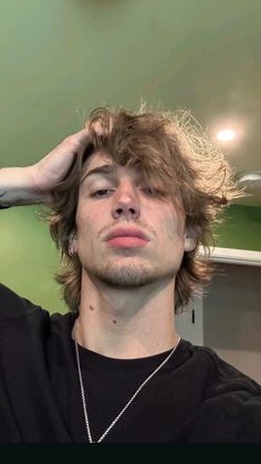 a young man with his hair in the air, holding his hands to his head