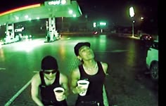 two people sitting on the ground with cups in their hands