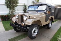 an old jeep is parked in front of a house