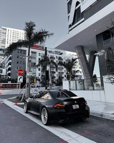 a black sports car parked in front of a tall building