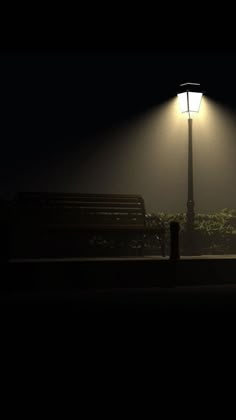 a bench sitting under a street light on a foggy night