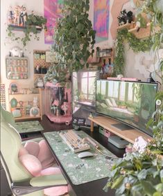 there is a desk with two monitors on it and some plants in the corner next to it