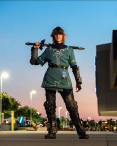 a woman in costume holding two swords on her shoulder and walking down the street at night