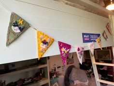 there are many colorful flags hanging from the ceiling and on the wall in this room