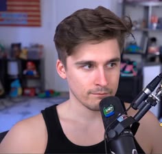 a man holding a microphone up to his face and looking at the camera while wearing a black tank top