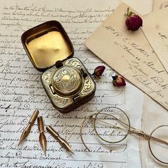an antique pocket watch sitting on top of a piece of paper next to some scissors