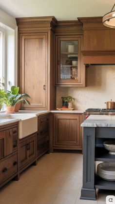 a kitchen with wooden cabinets and marble counter tops, an island in the middle is surrounded by pots and pans