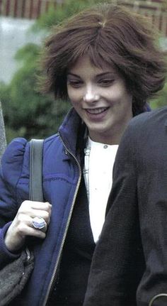 a woman walking down the street with her hand in her pocket and wearing a blue jacket