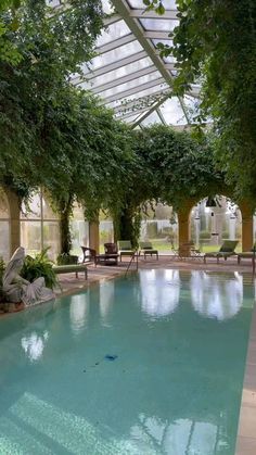 an indoor swimming pool surrounded by trees and chairs