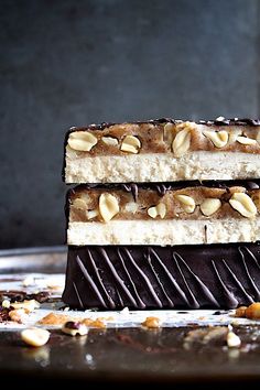 three pieces of cake sitting on top of a metal pan covered in chocolate and nuts