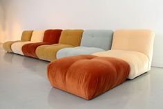 an orange, blue, yellow and white couch sitting on top of a cement floor