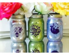 three painted mason jars with flowers in them