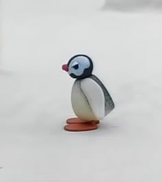 a small toy penguin is standing in the snow