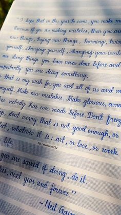 a piece of paper with writing on it sitting in the grass next to a tree