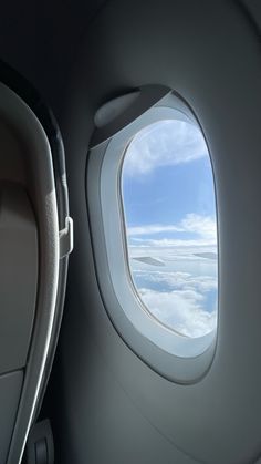 an airplane window with the view of clouds and blue sky from it's seat