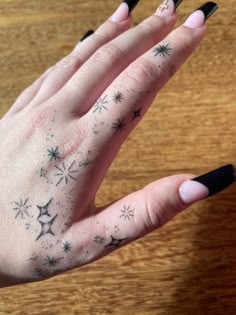 a woman's hand with black and white stars tattooed on her left index finger