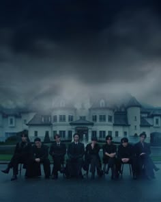 a group of people sitting on chairs in front of a large white building under a cloudy sky