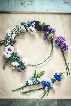 flowers arranged in the shape of a circle on top of a wooden board with green leaves