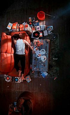 a man laying on top of a red couch next to a pile of junk and other items