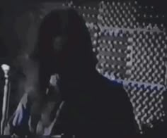 a man is talking on the phone in front of a microphone and an american flag