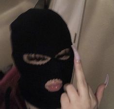 a person wearing a black mask and pointing at something